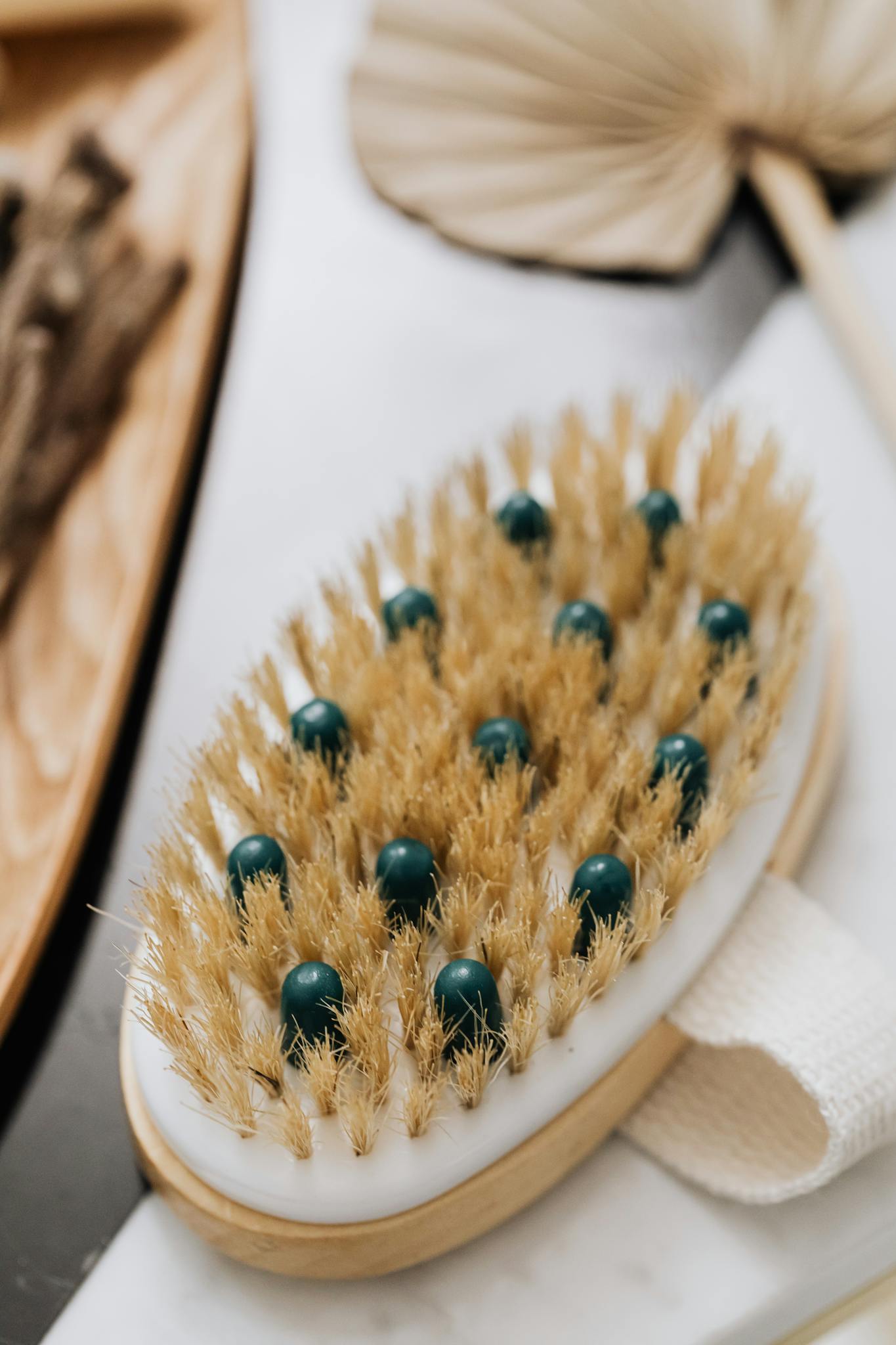 Close-up of an eco-friendly body brush with natural bristles and wooden base on marble surface.